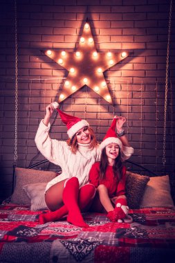 Noel şapkalı neşeli anne ve kız Star Il 'e karşı