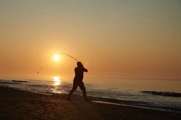 Sabahın köründe bir adam kıyıdan balık tutar.