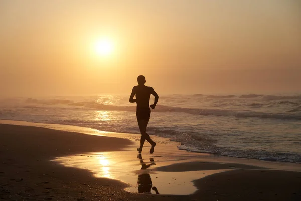 Ein Mann läuft morgens an der Küste des Meeres entlang Stockbild