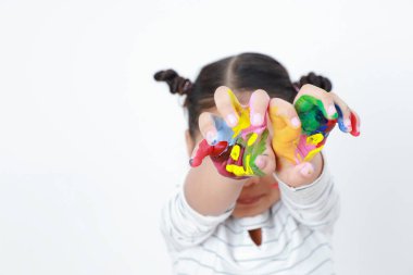Asyalı kız çocuklar ellerini yüzünü kaplayan renkli suyla gösteriyor, beyaz arka planda kopya alanı ile izole edilmiş. Sanatı öğrenmek eğlenceyi ifade eder. Eğitim, ilham ve fikirleri kabul et.