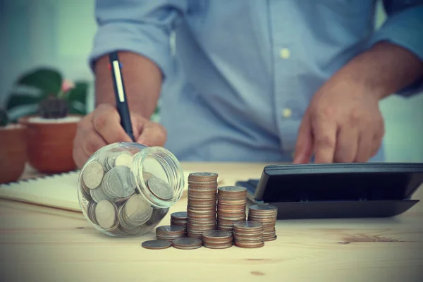 Tahta masaya bir sürü bozuk para kondu. Görünmez işadamının arkasında nakit hesapları, harcamalar ve kâr hesapları var. Konsept iş, mali, bankacılık ve muhasebe.