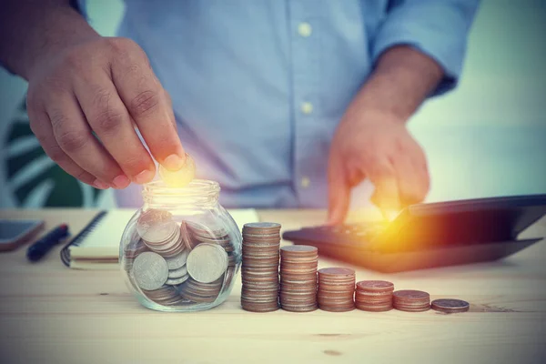 The businessman is picking up a coin in a glass jar to save in the future. Concept business, financial, banking, and accounting.