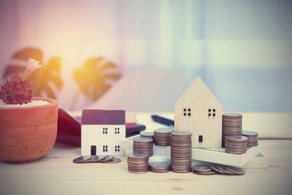 Model ev banknota kondu, bir sürü bozuk para ve hesap makinesi iş yerindeki masa tahtasının üzerinde. Konsept bankacılık, iş, muhasebe ve finans.