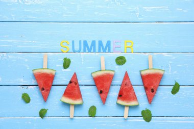 Nane şekerli karpuz dilimi yaz meyveleridir, yenilenmiş üst görünüm düzlüktür mavi ahşap masa zemininde fotokopi alanı ile birlikte uzanır.