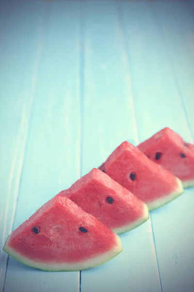 Karpuzu kapat ve eski mavi ahşap arka planda bazı ferahlatıcı parçaları fotokopi alanı ile doğra.