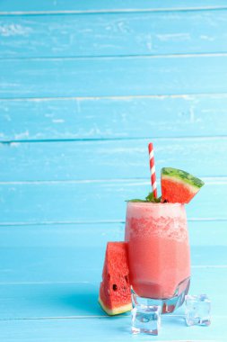 Fotokopi alanı olan eski mavi ahşap masa arkaplanındaki bardaktaki soğuk karpuz suyunu tazeliyorum. Yaz için içkiler.