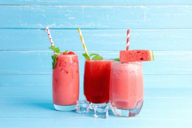 3 bardak karpuzlu smoothie dilimlenmiş ve mavi ahşap masa zemininde fotokopi alanı olan nane şekeri. Yaz için içkiler.