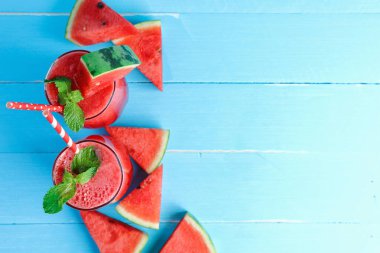 İçkiler yazın sağlığına iyi gelir. Bardakta soğuk karpuz suyu var. Üst görünüm, Düz mavi ahşap zemin üzerinde kopya alanı ile uzanır.