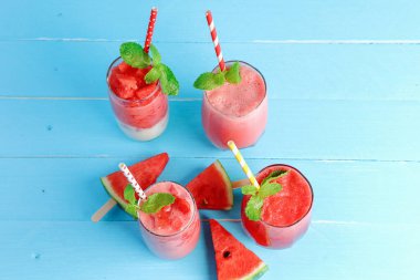 Yazın sağlığına içelim. Soğuk karpuz smoothie üst görünümü içer, mavi ahşap zemin üzerinde yatar fotokopi alanı ile.