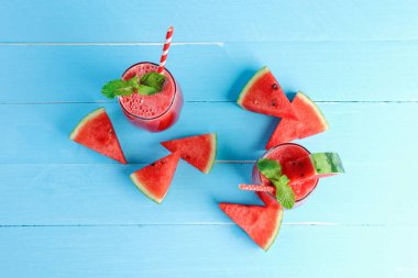 Yazın sağlığına içelim. Soğuk karpuz smoothie üst görünümü içer, mavi ahşap zemin üzerinde yatar fotokopi alanı ile.