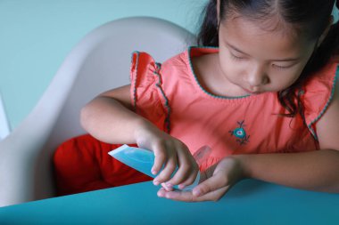 Koronavirüs salgınından dolayı. Evde eğitim almak için çocuklara internet üzerinden eğitim veren bir okul. Virüs ve bakterileri korumak için alkol jeli kullanan Asyalı küçük kız..