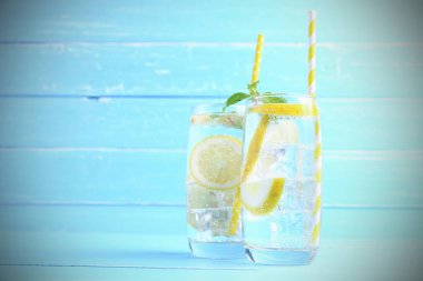 Yaz tatili. Meyve içecekleri. Limonlu soda, limonlu ve naneli olsun. Mavi ahşap arka plandaki bardakta da fotokopi alanı olsun. Bu yaz sağlığa içelim..