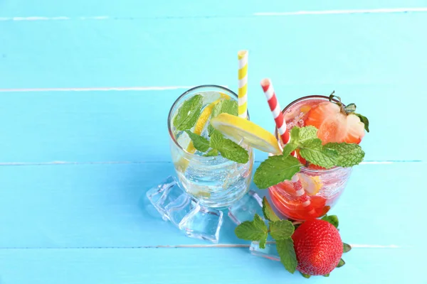Lemon juice and strawberry juice mixing soda no alcohol in the glass garnish with mint leaves, sliced lime, and half a strawberry on blue wooden table top view with copy space. Concept of summer drink.