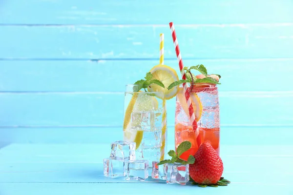 Strawberry juice and lemon juice mixing soda no alcohol in the glass garnish with mint leaves, sliced lemon on blue wooden table with copy space. Concept of summer drink.