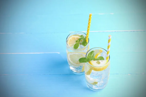 Refreshing summer some fruit drinks. Lemon juice mixing soda no-alcohol with slide lemon and mint in the glass on blue wooden background with copy space. Drinks for healthy this summer.