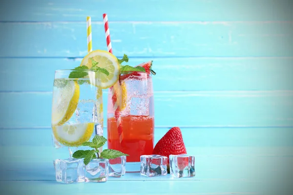 Limon suyu ve çilek suyu karıştırılmış soda bardakta alkol yok nane yapraklarıyla süslenmiş, mavi ahşap masada dilimlenmiş limon ve fotokopi alanı. Yaz içkisi kavramı.