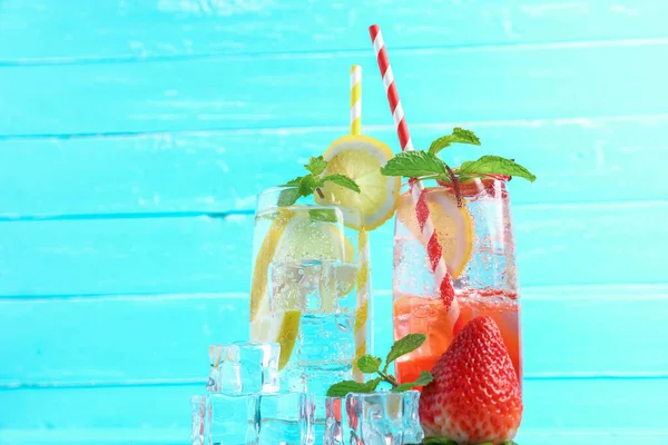 Strawberry juice and lemon juice mixing soda no alcohol in the glass garnish with mint leaves, sliced lime on blue wooden table with copy space. Concept of summer drink.