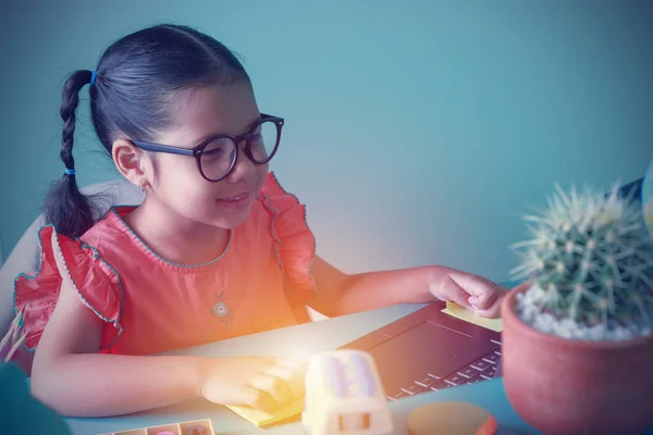 İnternetten eğitim interneti öğrenmek için dizüstü bilgisayara bakan Asyalı küçük kız. Koronavirüs salgını sırasında çocuklar evden öğreniyor. Yeni normal, sosyal uzaklık kavramı.