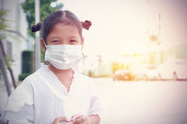 Koronavirüsü korumak için maske takan Asyalı şirin küçük kız. Herkese yeni normal yol, sosyal mesafe, alkollü jel temizleme, ellerini sık sık yıka..