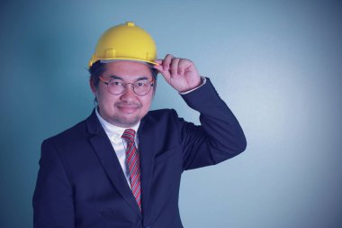 Siyah gözlüklü Asyalı işadamı mühendisliği yüksek özgüvenli gülümseyen mutluluğa sahip. Fotokopi alanı olan sarı bir şapka takıyor..