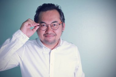 Asyalı iş adamının gözlük taktığına dair kendine güveni yüksek ve yeşil arka planda duran beyaz gömleği fotokopi alanı var. Erkekler başarılıdır..