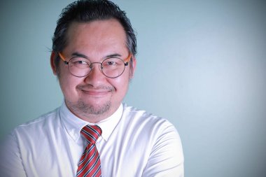 Asyalı işadamı gözlük takıyor ve mutlu bir şekilde gülümsüyor. Gözlük takan bir adam kendinden emin hissediyor. Yakın plan portresi olan adam, yeşil arkaplanda fotokopi alanı olan kameraya bakıyor..