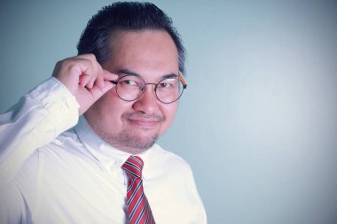 Fotoğraftaki adam kameraya fotokopi çekerek gülümsüyor. Asyalı iş adamı yeşil arka planda başarılı görünüyor. Gözlüklü bir adam kendinden emin hissediyor..