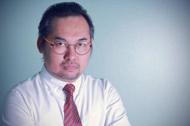 Asyalı iş adamı yeşil arka planda başarılı görünüyor. Fotoğraftaki adam kameraya fotokopi çekerek gülümsüyor. Gözlüklü bir adam kendinden emin hissediyor..