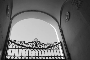 Evin kemerinde dövülmüş demir bir kapının monokrom görüntüsü. Katı kapı çizgileri ve kemerin eğrisinin ilginç bir kombinasyonu gibi geldi bana..