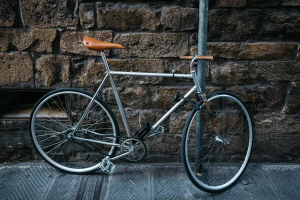 古い石の壁を背景にパイプに固定された古いレトロな自転車 — ストック写真