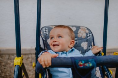 Bahçedeki bebek arabasında güzel bir beyaz çocuk.