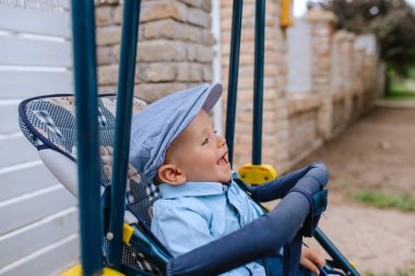 Bahçedeki bebek arabasında şapkası olan güzel bir çocuk.
