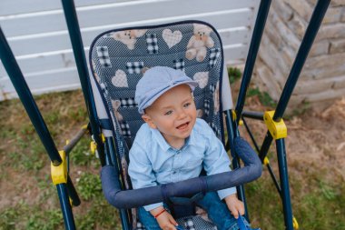 Bahçedeki bebek arabasında şapkası olan güzel bir çocuk.