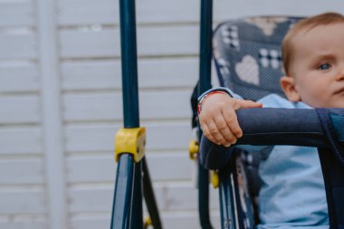 Bahçedeki bebek arabasında güzel bir beyaz çocuk.