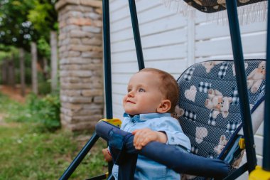 Bahçedeki bebek arabasında güzel bir beyaz çocuk.
