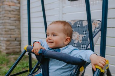 Bahçedeki bebek arabasında güzel bir beyaz çocuk.