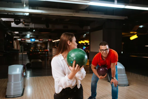 A beautiful caucasian man and woman on a bowling alley with balls. Love and recreation