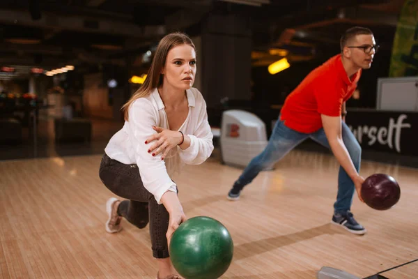 A beautiful loving caucasian couple throwing balls on the bowling alley. Boyfriend and girlfriend at the bowling club