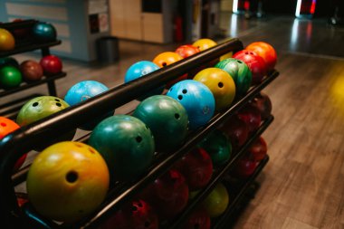 Bowling kulübünün rafında çok renkli bowling topları var.