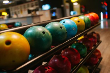Bowling kulübünün rafında çok renkli bowling topları var.