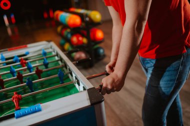 Masa futbolu oynarken kırmızı tişörtlü beyaz bir adamın elleri yakın plan.