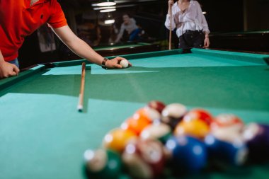 Kırmızı tişörtlü beyaz bir adam topları bilardo masasına yerleştiriyor. Eğlence zamanı. 