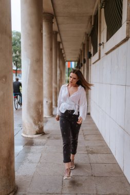 Sütunları olan beyaz bir binanın önünde güzel bir beyaz kız.