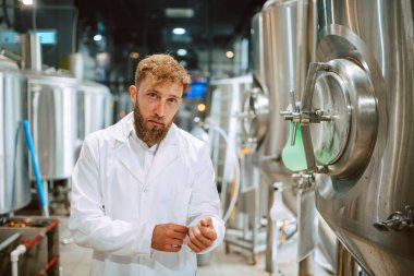  İlaç veya gıda fabrikasında duran beyaz üniforma konusunda uzman beyaz tenli yakışıklı teknoloji uzmanının portresi.