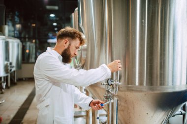 Üretim fabrikasındaki endüstriyel süreci kontrol eden Kafkas Teknoloji Uzmanı. Koruyucu üniformalı sanayi işçisi gıda fabrikasındaki verimliliği kontrol ediyor..