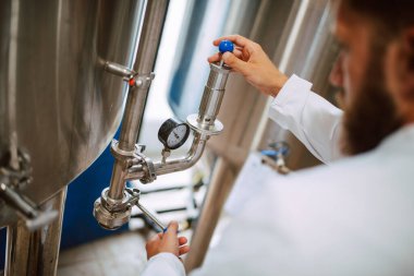 Üretim fabrikasındaki endüstriyel süreci kontrol eden Kafkas Teknoloji Uzmanı. Koruyucu üniformalı sanayi işçisi gıda fabrikasındaki verimliliği kontrol ediyor..