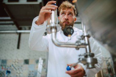 Üretim fabrikasındaki endüstriyel süreci kontrol eden Kafkas Teknoloji Uzmanı. Koruyucu üniformalı sanayi işçisi gıda fabrikasındaki verimliliği kontrol ediyor..