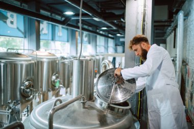 Üretim fabrikasındaki endüstriyel süreci kontrol eden Kafkas Teknoloji Uzmanı. Koruyucu üniformalı sanayi işçisi gıda fabrikasındaki verimliliği kontrol ediyor..