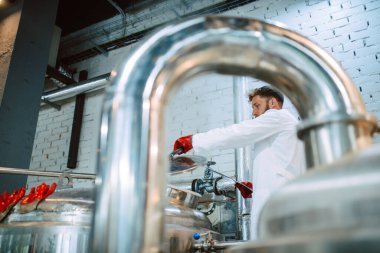  Üretim fabrikasındaki endüstriyel süreci kontrol eden eldiven uzmanı. Koruyucu üniformalı sanayi işçisi gıda fabrikasındaki verimliliği kontrol ediyor..