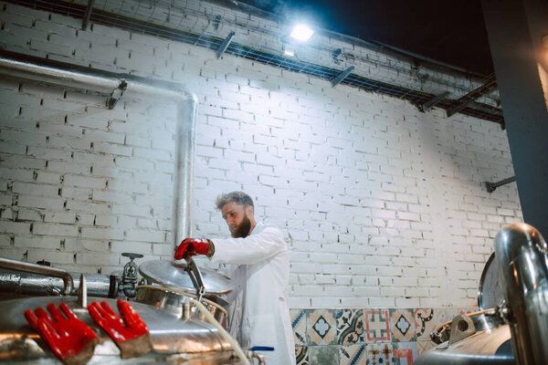  Professional caucasian technologist expert in gloves controlling industrial process in production plant. Industrial worker with protective uniform checking productivity in food factory.